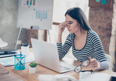 Overworked tired secretary holding spectacles and touching her nose bridge